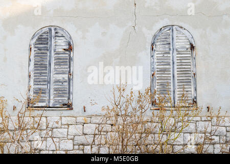 Detail von zwei alten Fenster mit geschlossenen Holzbalkons in einem verlassenen Haus. Stockfoto