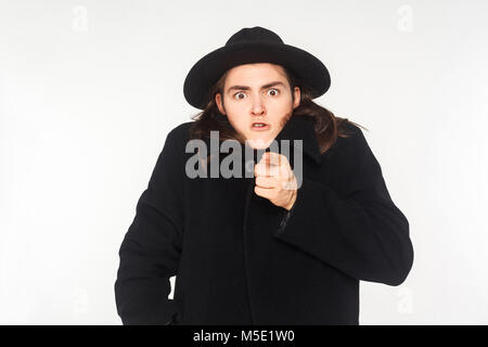 Lustiger Mann im Mantel Zeigefinger an Kamera und haben einen schockierten Blick. Studio shot Stockfoto
