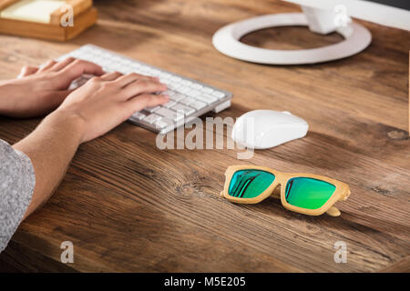 Foto von Holz- Sonnenbrille auf Schreibtisch am Arbeitsplatz Stockfoto
