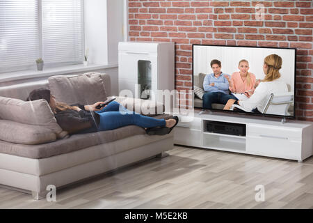 Junge Frau mit auf der Couch vor dem Fernseher zu Hause Stockfoto