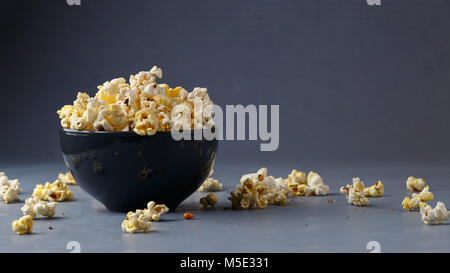 Popcorn in der Schüssel über grauen Hintergrund. Platz für Ihren Text