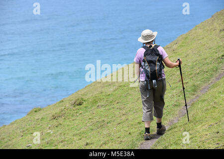 Eine weibliche Wanderer mit einer Wanderung der Pole mit Blick auf das Wasser auf den Spuren von Coffee Bay am Indischen Ozean im östlichen Kap an der wilden Küste von S Stockfoto