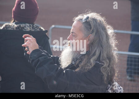 Mann mit langen Haaren, Bart und Zigarette ein Foto auf einem Smartphone mit Sonnenbrille auf dem Kopf vor dem Buckingham Palace Stockfoto