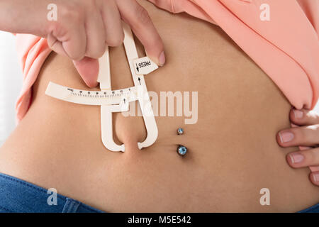 Frau mit Fat Caliper zu messen Körperfett auf Taille Stockfoto