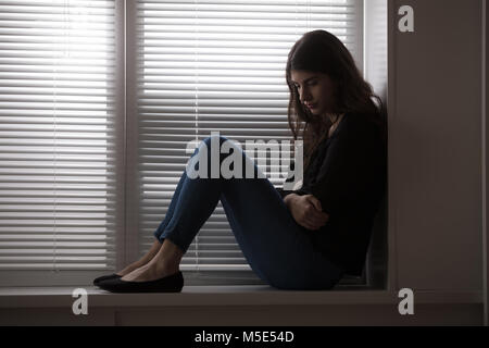 Junge gedrückt Frau sitzt auf der Fensterbank Stockfoto