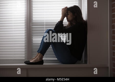 Junge gedrückt Frau sitzt auf der Fensterbank Stockfoto