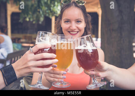 Weibliche Toasten und jubelnden Aperitif Bier 0,33 Liter mit Ihren Freunden im Restaurant Stockfoto