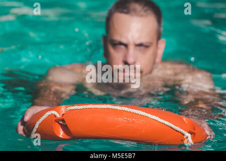 Schwimmer mit Rettungsring in Wasser. Lebensrettende Konzept Stockfoto