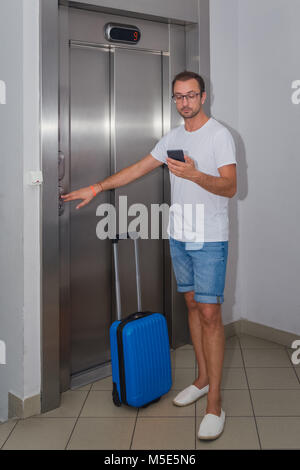 Portrait von jungen Touristen Kerl, der Aufzug und Abrufen von Nachrichten auf seinem Smartphone. Reisen und Sommerurlaub Konzepte Stockfoto