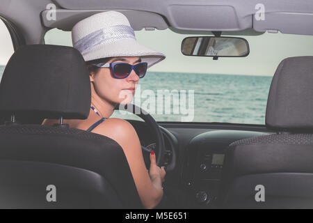 Portrait von modischen jungen weiblichen im Fahrersitz im Innenraum. Meer im Hintergrund. Reisen, Transport und Sommerurlaub Konzepte. Stockfoto