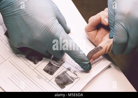 Die Forscher nehmen Fingerabdrücke von der Verdächtige in der Kriminalität. Die Untersuchung ist ein Verbrechen. Kriminalität. Stockfoto