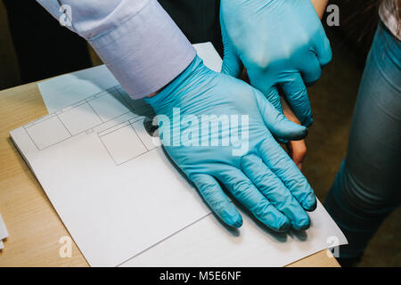 Die Forscher nehmen Fingerabdrücke von der Verdächtige in der Kriminalität. Die Untersuchung ist ein Verbrechen. Kriminalität. Stockfoto