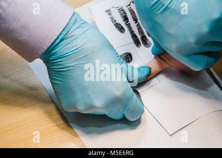 Die Forscher nehmen Fingerabdrücke von der Verdächtige in der Kriminalität. Die Untersuchung ist ein Verbrechen. Kriminalität. Stockfoto