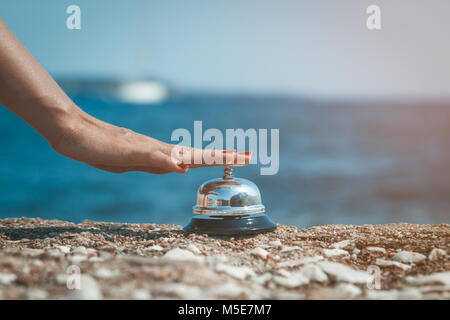 Weibliche drücken läutenden Glocke am Meer. Sommer Urlaub und Reisen Konzepte. Stockfoto