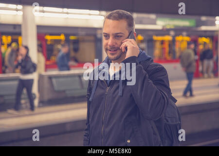 Urban Kerl mit Smartphone bei der Metro U-Plattform. Stockfoto