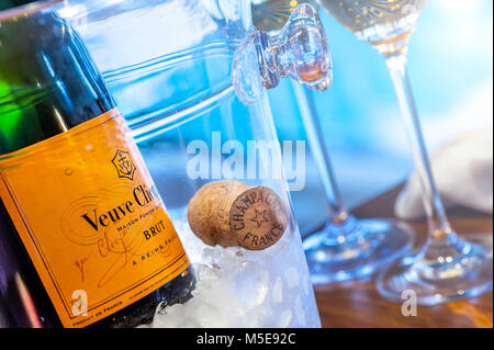 Veuve Clicquot feine Champagner-Flasche auf Eis mit Kork und Gläsern, Luxus-Ambiente, Pool im Hintergrund mit Sonnenuntergang am späten Nachmittag Stockfoto