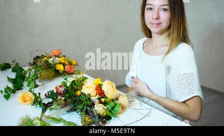 Wunderbare weibliche floral Dekorateur beschäftigt sich mit Kamera und lächelt, s Stockfoto