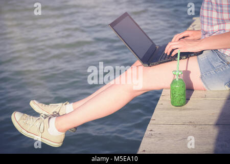 Frauen sitzen auf dem Pier und Arbeiten am Laptop. Sommer Urlaub und Freiberufler Konzepte. Stockfoto