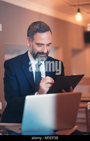 Senior älteren Geschäftsmann Ausfüllen etwas Papier arbeiten, trinken Kaffee in einem Cafe Stockfoto
