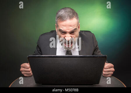 Senior Business Mann an seinem Laptop schreien, wütend und frustriert mit einer E-Mail erhält er Stockfoto