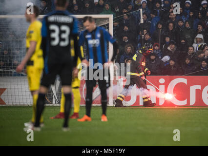 22. Februar 2018, Italien, Bergamo: Fußball, UEFA Europa League, Runden von 32, 2.Etappe: Atalanta Bergamo vs Borussia Dortmund. Ein Feuerwehrmann (R, Zurück) trägt eine brennende Fackel auf dem Spielfeld. Foto: Bernd Thissen/dpa Stockfoto