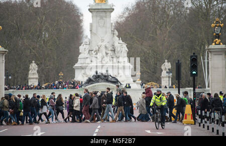 Westminster, London, Großbritannien. 23. Februar 2018. Touristen Kreuzung Sporn Straße bitterkalten Wind trotzen dem Ändern der Guard Zeremonien im St James's Palace und Buckingham Palace zu beobachten. Credit: Malcolm Park/Alamy Leben Nachrichten. Stockfoto