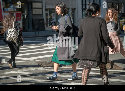 Ein Fußgänger überprüft Ihr Smartphone während ein Schnittpunkt der Fifth Avenue in New York crossing am Mittwoch, 21. Februar 2018. (Â© Richard B. Levine) Stockfoto