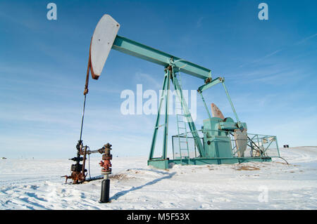 Alberta, Kanada. Öl gut pumpjack auf die Wiesen an einem sonnigen Tag im Winter. Stockfoto