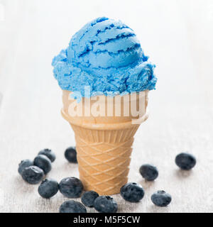 Blaue Eis in der Waffel Kegel mit Heidelbeeren auf weißem Holz- Hintergrund. Stockfoto