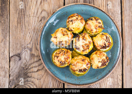 Zucchini gefüllt mit Fleisch und Käse auf blauen Platte. Studio Foto Stockfoto