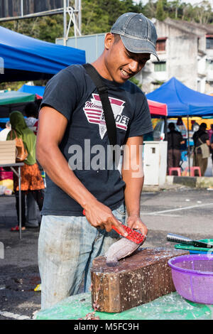 Cameron Highlands, Malaysia, 17. Dezember 2017: Verkäufer schabt die Schuppen der Fische mit einem Messer Stockfoto