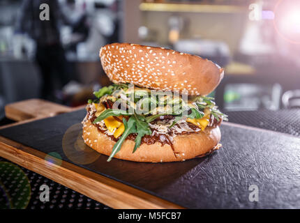 Lecker gegrilltes Rindfleisch Burger mit Rakete auf schiefer Board serviert Stockfoto