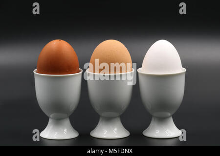 Braun bis drei Frühstück Eier in eggcup auf schwarzem Hintergrund Stockfoto