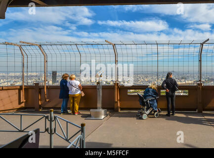 Touristen, darunter eine Frau im Rollstuhl genießen Sie den Blick auf die Stadt Paris an einem sonnigen Tag von der ersten Plattform des Eiffelturms in Paris Frankreich Stockfoto