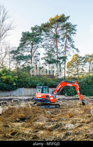 Große orange schwere Anlage mechanische Bagger auf einer Baustelle geparkt nach graben Ausgrabungen für die Grundlagen einer neuen Wohnanlage Stockfoto