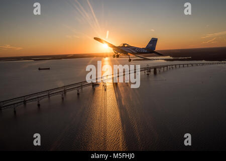 Blue Vans RV-12 Light Sport Aircraft in Richtung der untergehenden Sonne über die Chesapeake Bay Bridge, Stevensville, Maryland fliegen. Stockfoto