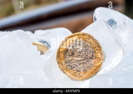 Gefrorene Neue Britische Pfund Sterling coin Nahaufnahme Makro innerhalb von Eiswürfeln. Stockfoto