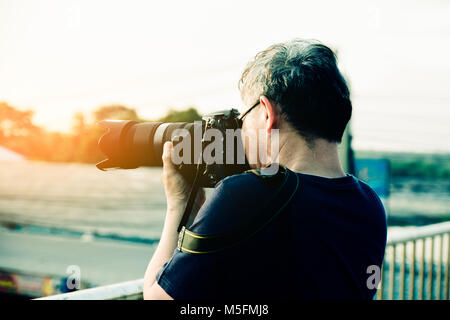 Mann mit Kamera, DSLR, Foto Sonnenlicht Hintergrund Stockfoto