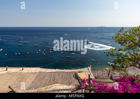 Positano, Italien, 12. Juni 2017: Positano durch rosafarbene Bougainvillea und Boote im Hintergrund eingerahmt. Bunte Positano, die Perle der Amalfiküste, Stockfoto