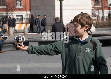 Ein junger Mann, wahrscheinlich ein Tourist, speist die Tauben im Washington Square Park in Greenwich Village, Manhattan, New York City Stockfoto