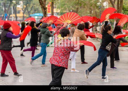 Eine Gruppe von älteren Frau mit rotem Papier Ventilatoren Praxis früh am Morgen Tai Chi am Ho Hoan Kiem See, Hanoi, Vietnam Stockfoto