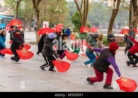 Eine Gruppe von älteren Frau mit rotem Papier Ventilatoren Praxis früh am Morgen Tai Chi am Ho Hoan Kiem See, Hanoi, Vietnam Stockfoto