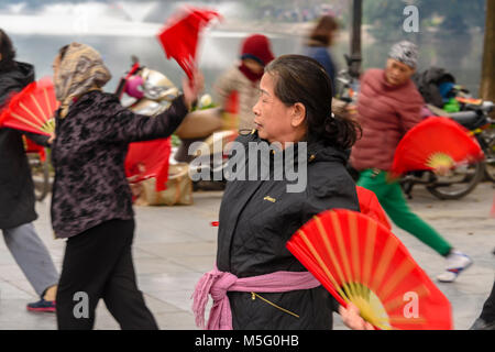 Eine Gruppe von älteren Frau mit rotem Papier Ventilatoren Praxis früh am Morgen Tai Chi am Ho Hoan Kiem See, Hanoi, Vietnam Stockfoto