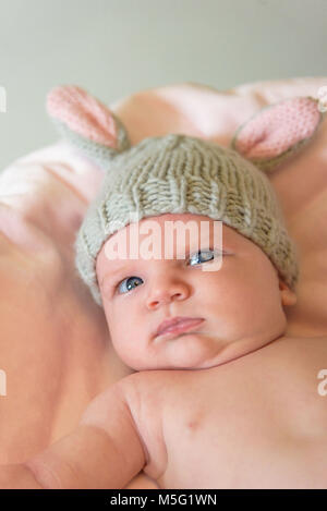 Lustige Nahaufnahme eines Babys in einem hausgemachten Stricken bunny Ohr Hut auf Ostern Stockfoto