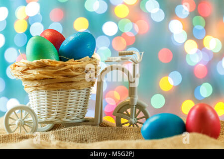Ostern Karte, farbige Eier im Nest. Spielzeug Fahrrad mit einer Karre. Frohe Ostern. Zarte blau Hintergrund. Für Text platzieren. Stockfoto
