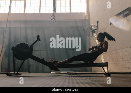 Frau tun cardio Workout am Rudergerät in der Turnhalle. Weibliche trainieren im Fitness Club. Stockfoto