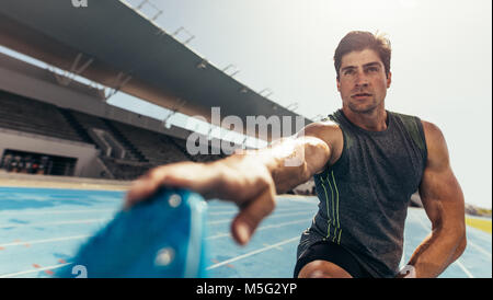 Athleten zu tun Stretching Übungen auf der Laufstrecke. Läufer stretching Beinmuskeln durch seine Schuhe zu berühren. Stockfoto