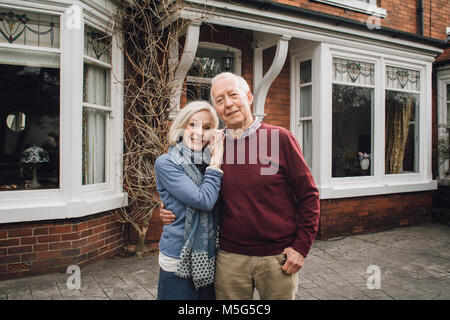 Senior Paar, Lächeln für die Kamera, während vor ihrem Haus stehen. Stockfoto