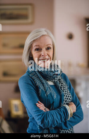 Porträt einer älteren Frau mit ihren Armen in ihrem Haus gefaltet. Stockfoto