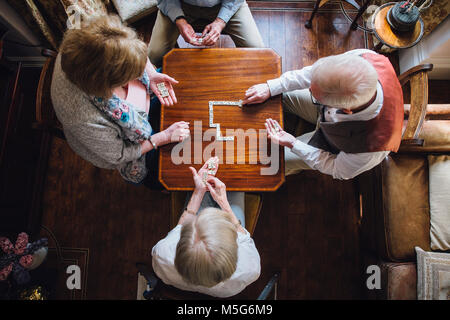 Luftaufnahme von vier ältere Erwachsene Domino spielen auf einem Tisch im Pflegeheim. Stockfoto